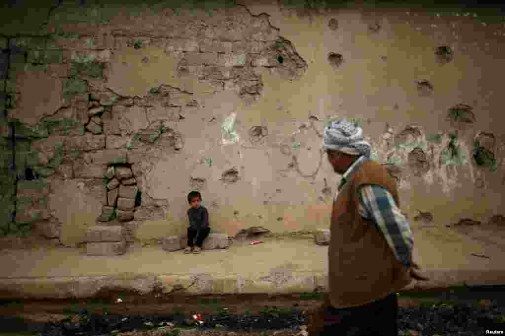 An Iraqi boy sits outside a house that was damaged during the fighting between Iraqi forces and Islamic State militant in Hammam al-Alil city, south of Mosul, Iraq. (Reuters/Suhaib Salem)