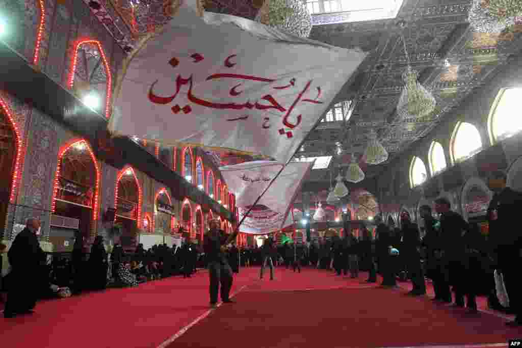 A Shi'ite Iraqi Muslim pilgrim waves a flag with the Arabic inscription "Oh Hussein" as people prepare for an Ashura ceremony in Karbala, the city where Imam Hussain died in battle in 680 A.D. (AFP/Ahmad al-Rubaye)