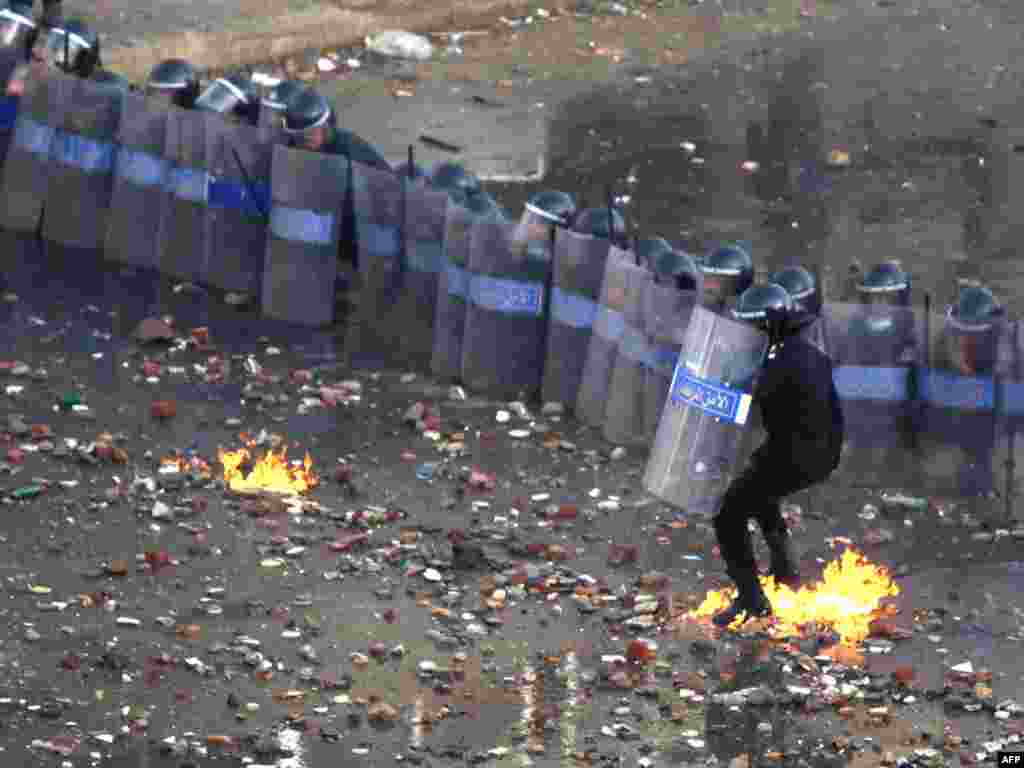 A police officer catches fire from a fire bomb thrown at police battling demonstrators in Suez January 27.