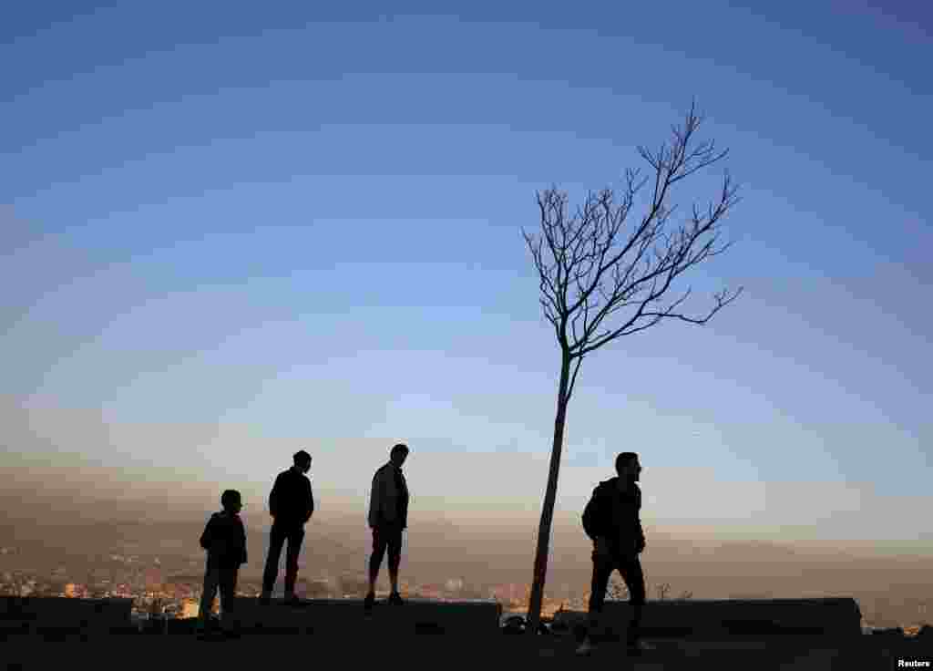 People stand next to a tree overlooking Kabul city on February 1. (Reuters/Ahmad Masood)