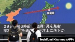 Токионун тургундары Түндүк Кореянын соңку ракетасы тууралуу жаңылыкты көчөдөгү экрандан көрүп жатышат, 29-август 2017-жыл.