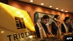 Receptionists answer telephones at the front desk of the reopened Trident Hotel in Mumbai.