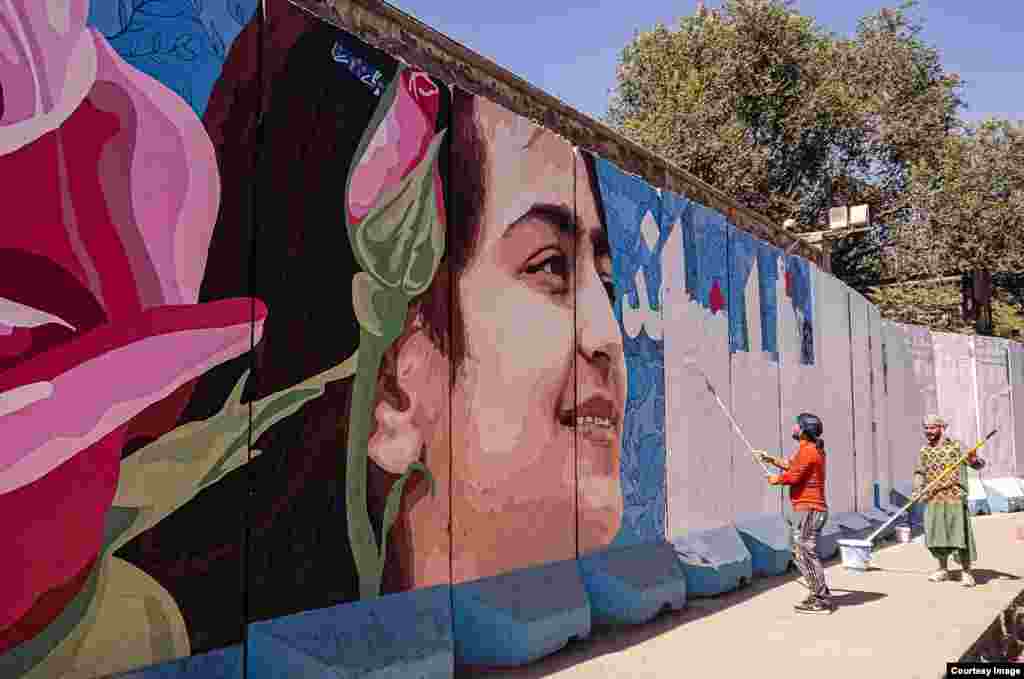 Workers paint over a mural featuring a young woman&rsquo;s face. The men are professional sign writers, who later painted various slogans and pro-Taliban murals over the wall. The painters said they had been hired by the Taliban for the job. &nbsp;