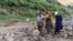 په ګلګت بلتستان کې مرستندویه کارکوونکي له سېلابه ژغورلی کس خوندي ځای ته لېږدوي - د جولای ۲۲مې انځور.