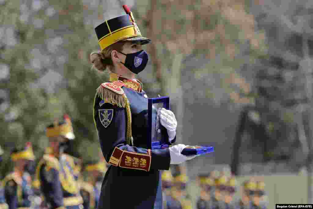 A member of Romania&#39;s main honor guard regiment waits to deliver an official medal during ceremonies marking 100 years since the inauguration of the Cantacuzino National Institute for Medical-Military Research and Development in Bucharest. Cantacuzino is Romania&#39;s main research facility for the development of vaccines against various diseases. (epa-EFE/Bogdan Cristel)