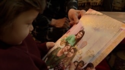 Духтари Рухшона Ҳакимова ба акси модараш нигоҳ мекунад. Ин хабарнигор дар доираи парвандаи ба ном "талоши табаддулот" соли 2025 ба 8 соли зиндон маҳкум шуд   