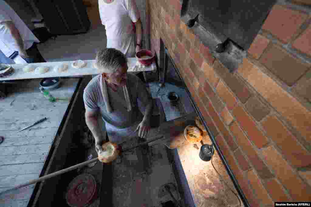 Pamje nga lart e bukëpjekësit duke i nxjerrë nga furra pitalkat e pjekura dhe të gatshëm për t’u shërbyer.