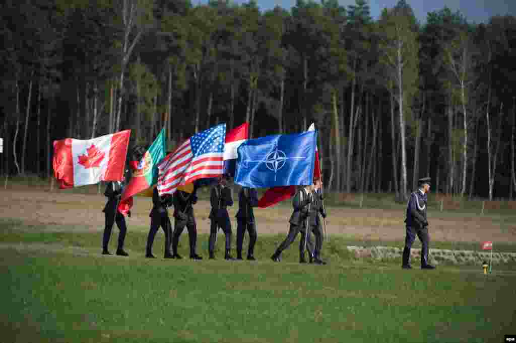 NATO military personnel walk with their nation&#39;s flags during final preparations before the alliance&#39;s Secretary-General Jens Stoltenberg&#39;s visit to an airbase in Lask, Poland, on October 6.&nbsp;(epa/Grzegorz Michalowski)&nbsp; 