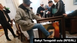 Захватившие правительственное здание протестующие сняли портрет президента Кыргызстана Сооронбая Жээнбекова, один из мужчин выбивает его из рамы. Бишкек, 6 октября 2020 года.