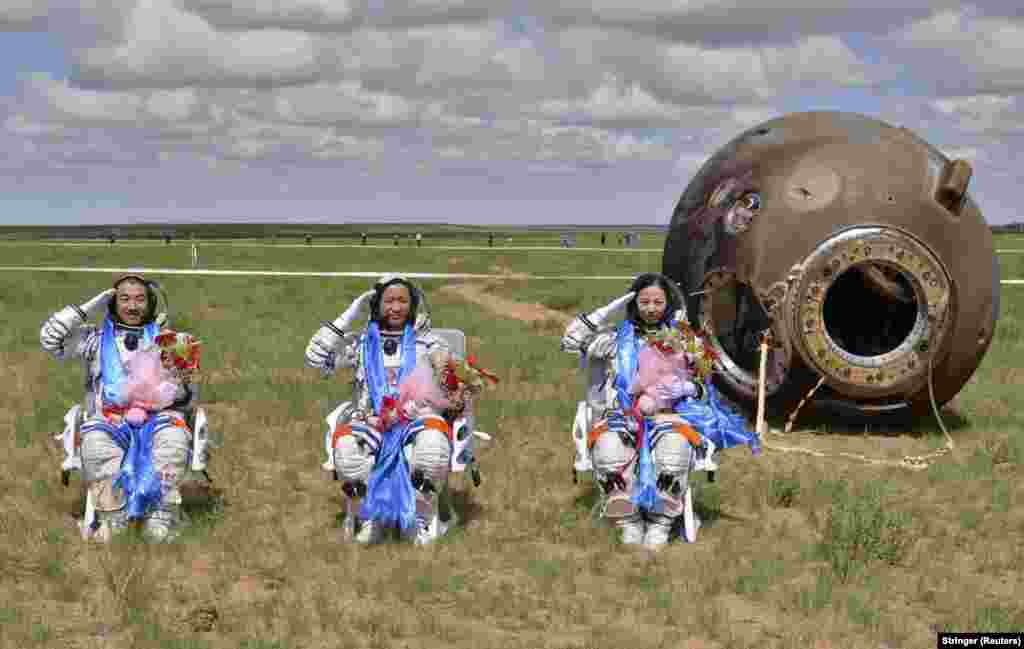 Chinese astronauts Zhang Xiaoguang (left), Nie Haisheng (center), and Wang Yaping salute after returning to Earth in the reentry capsule of China's Shenzhou-10 spacecraft at its main landing site in the Inner Mongolia Autonomous Region. The astronauts successfully completed a 15-day mission. (Reuters)