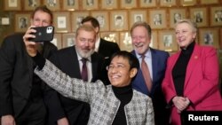 A Nobel-békedíjas Maria Ressa szelfit készít a Nobel-bizottság tagjaival és a vele együtt kitüntetett Dmitrij Muratovval az oslói Nobel Intézetben 2021. december 9-én