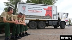 New Russian soldiers sit next to a mobile recruitment center for military service in Rostov-on-Don, Russia, in September 2022. 