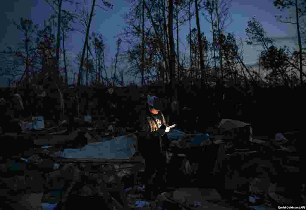 Matthew Schell looks for personal mementos by flashlight at dusk in the rubble of his house, which was destroyed by a tornado that killed his uncle, David Wayne Dean, in Beauregard, Alabama. Twenty-three people were killed in a series of twisters. (AP/David Goldman)