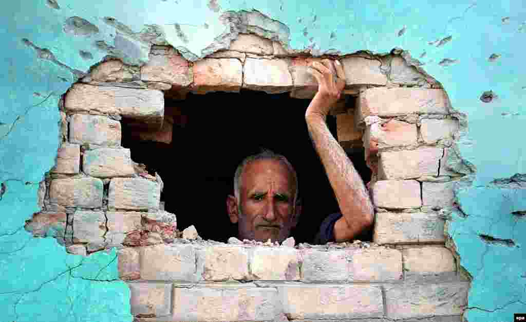 An Indian villager looks from a hole in the wall of a building allegedly damaged by shelling from the Pakistani side of the disputed Kashmir border. (epa/Jaipal Singh)