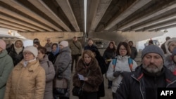 Local residents attend a memorial ceremony under a destroyed bridge in Irpin, northwest of Kyiv, on February 24, 2025, on the third anniversary of Russia's full-scale invasion of Ukraine. 