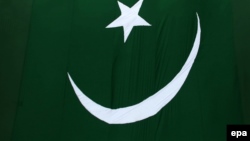 Pakistan -- A woman waves Pakistan's national flag during a ceremony to mark the country's 69th Independence Day at the Wagah border near Lahore, August 14, 2015. 