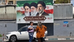 Women stand on a street in Tehran in front of a billboard with portraits of the three men who have been supreme leaders of the Islamic republic: Ayatollah Ruhollah Khomeini (left), Ayatollah Ali Khamenei (center), and the incumbent, Mojtaba Khamenei. 