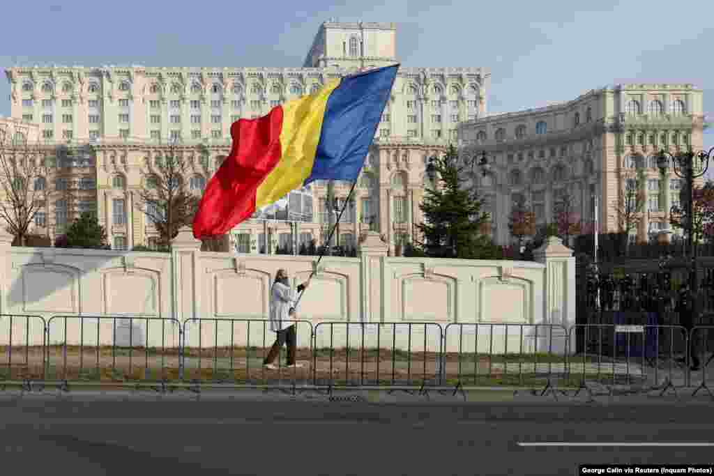 A supporter of Romania's populist presidential candidate Calin Georgescu waves the country's flag in front of Bucharest's Palace of the Parliament on January 10. Protests broke out in early January after Romania's Constitutional Court canceled the second round of presidential elections after Georgescu unexpectedly won the first round.Photo by George Calin/Inquam Photos