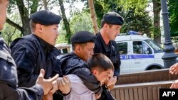 Kazakh policemen detain an opposition activist during a rally in Almaty in June 2018.