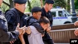 Полиция қызметкерлері алаңға келген адамды әкетіп бара жатыр. Алматы, 23 маусым 2018 жыл.