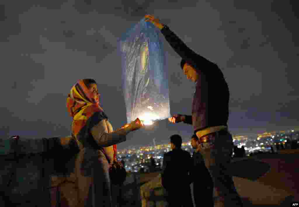 An Iranian couple lights a lantern in a park in Tehran as part of festivities ahead of the annual spring festival of Norouz. (AFP)