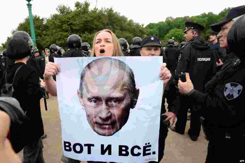 A woman holds a poster bearing a portrait of Russian President Vladimir Putin and reading, "That's All" during an unauthorized opposition rally in the center of St. Petersburg on June 12. Some 1,150 people were detained at rallies across the country. (AFP/Olga Maltseva)