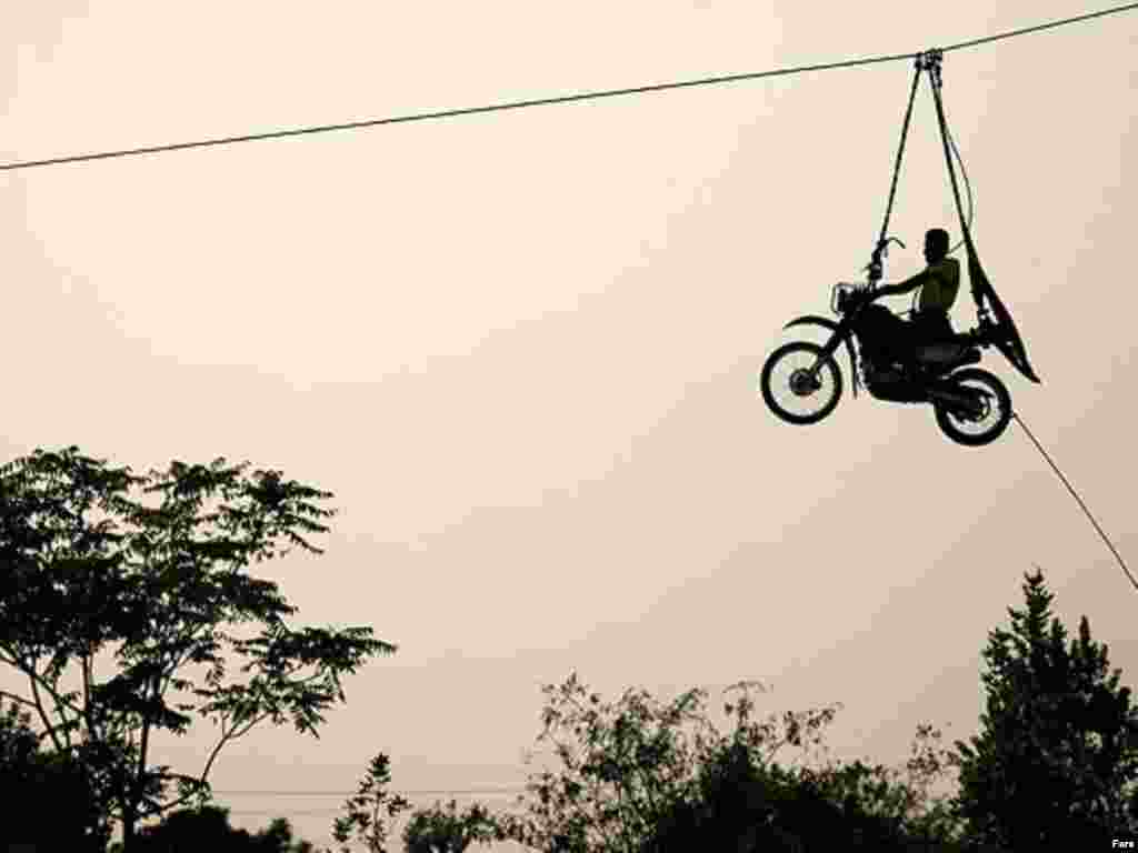 Iran – A man at motorcycle transports by cable during exercise of Iranian police force called “Eghtedar”, Oct2010 - Iran – A man at motorcycle transports by cable during exercise of Iranian police force called “Eghtedar”, Oct2010