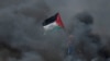 Dječak drži palestinsku zastavu dok stoji usred dima uoči 70. godišnjice Nakbe, na granici Izraela i Gaze istočno od grada Gaze 14. maja 2018. 