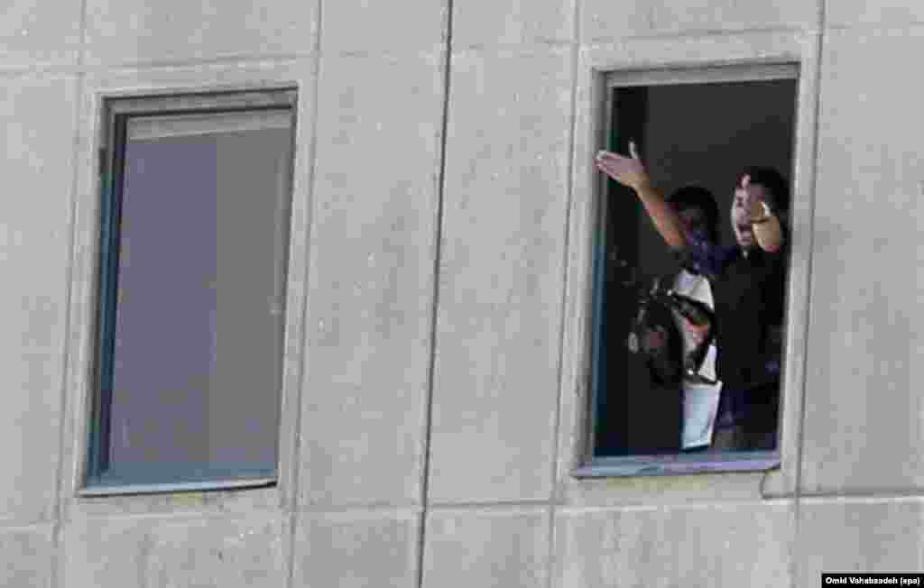 Armed policemen shout from a window of the Iranian parliament building.