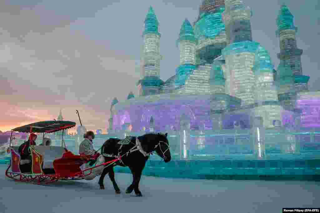 Visitors sit in a horse-drawn carriage in front of ice sculptures in Harbin in China&#39;s Heilongjiang Province. (epa-EFE/Roman Pilipey)