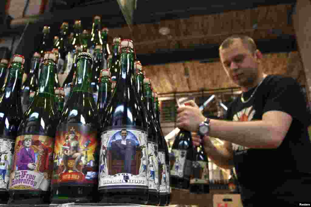 An employee arranges bottles of beer depicting German Chancellor Angela Merkel, Russian President Vladimir Putin, and U.S. President Barack Obama on its labels, at the Pravda Beer Theatre brewery in Lviv, western Ukraine. (Reuters/​Roman Baluk)&nbsp;