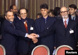 Rexhep Qosja, i pari djathtas, bashkon duart me anëtarë të tjerë të delegacionit të Kosovës pas nënshkrimit të një plani simbolik ndërkombëtar për paqe, në një ceremoni në Qendrën e Konferencave në Paris, më 18 mars 1999.