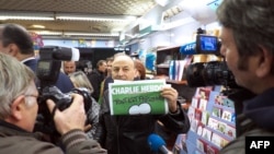 Франциядағы Charlie Hebdo журналының жаңа номерін көрсетіп тұрған адам. Марсель, 14 қаңтар 2015 жыл.