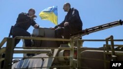 Arseniy Yatsenyuk (right) sits atop an armored vehicle during a visit to a checkpoint near the eastern Ukrainian city of Slovyansk on May 7, 2014.