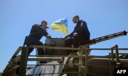 Арсений Яценюк (справа) сидит на бронетранспортере во время посещения блокпоста возле восточноукраинского города Славянск. 7 мая 2014 года.