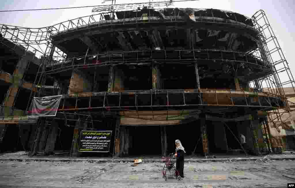 An Iraqi woman walks on July 4 past a building damaged by a suicide-bombing attack that took place a day earlier in Baghdad&#39;s Karrada neighborhood, killing scores of people. (AFP/Ahmad al-Rubaye)