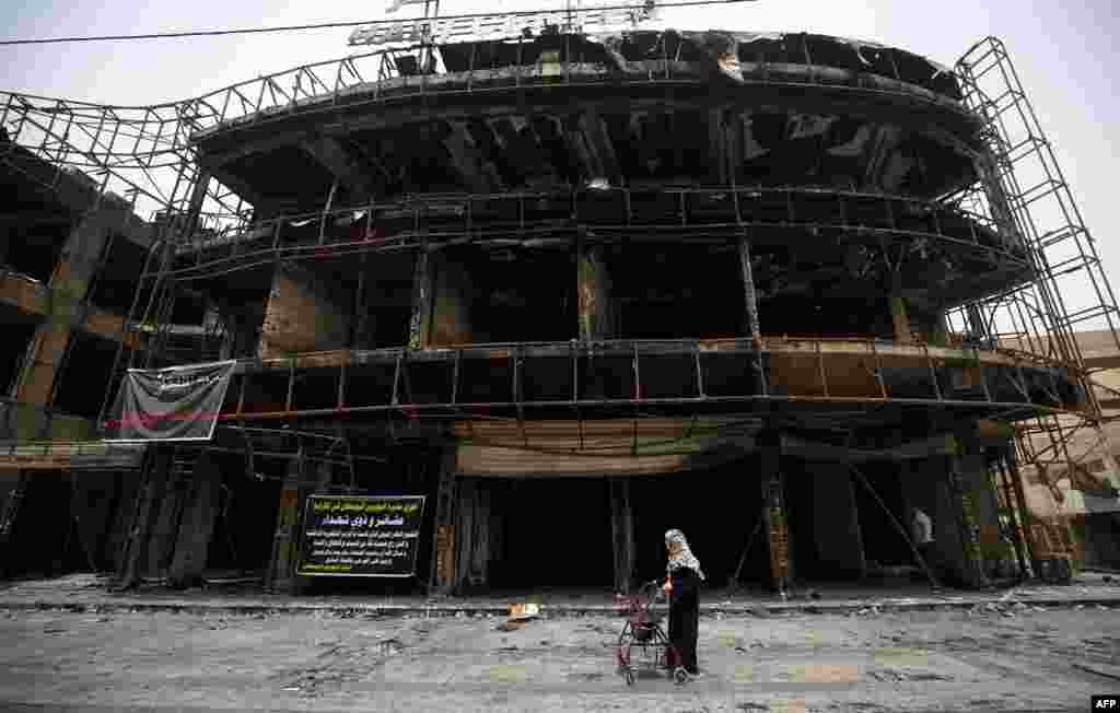 Bir aýal Bagdadyň Karrada etrabynda 4-nji iýulda janyndan geçeniň özüni partladan ýerinden ýöräp barýar. Bu wakada onlarça adam öldi. (AFP/Ahmad al-Rubaye)