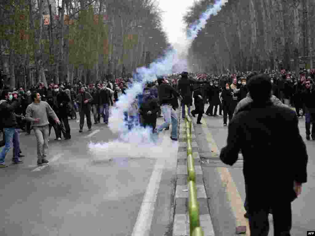 Some of the thousands who reportedly came out to protest in Tehran scatter as a tear-gas canister lands. (AFP)