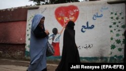 Авганистанки поминуваат покрај sид со графит на кои пишува „Мир“ во Херат, 3 мај 2021 година