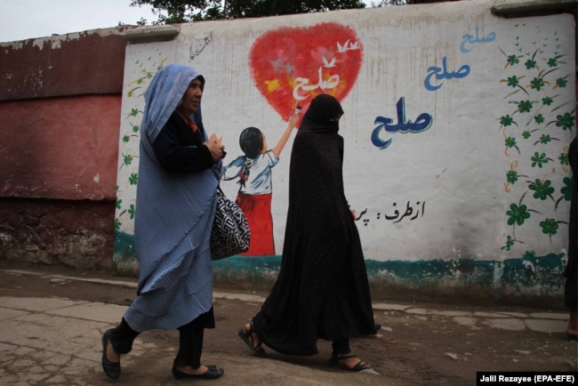 Афганские женщины проходят мимо стены с надписью: «Мир» — в Герате, 3 мая 2021 года