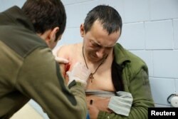 Un medic din armata ucraineană îl îngrijește pe militarul rănit Denys, în vârstă de 34 de ani, la o clinică medicală de campanie, în regiunea Donețk, Ucraina, 30 decembrie 2022.