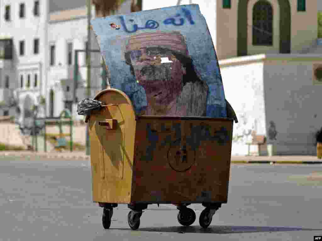 A poster of Libya&#39;s ousted strongman Muammar Qaddafi sits in a garbage container on a deserted street in Tripoli. (Photo by Patrick Baz for AFP)