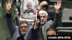 Iranian lawmakers holding pictures of slain Iran's Qods Force leader Qassem Soleimani as they chant 'death to America', during a parliament session in Tehran, January 7, 2020