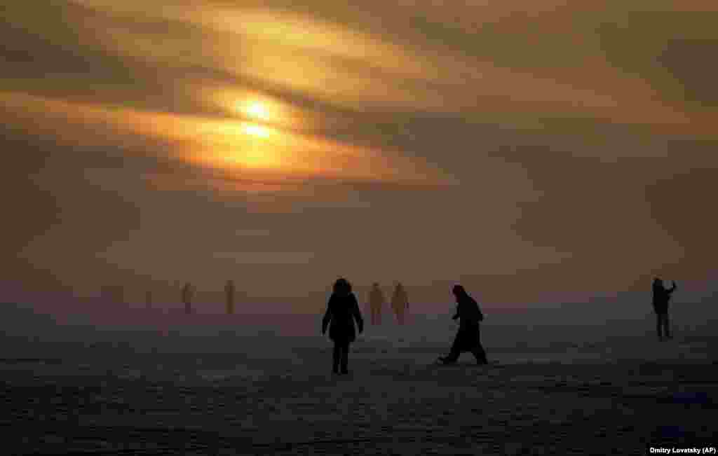 People walk on ice of the Finnish Gulf in the fog in St. Petersburg. (AP/Dmitry Lovetsky)