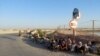 Afghan border guards who fled to Tajikistan after a Taliban attack sit on the side of the road on June 22.