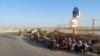 Afghan border guards who fled to Tajikistan after a Taliban attack sit on the side of the road on June 22.