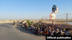 Afghan border guards who fled to Tajikistan after a Taliban attack sit on the side of the road on June 22.