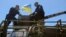 Arseniy Yatsenyuk (right) sits atop an armored vehicle during a visit to a checkpoint near the eastern Ukrainian city of Slovyansk on May 7, 2014.