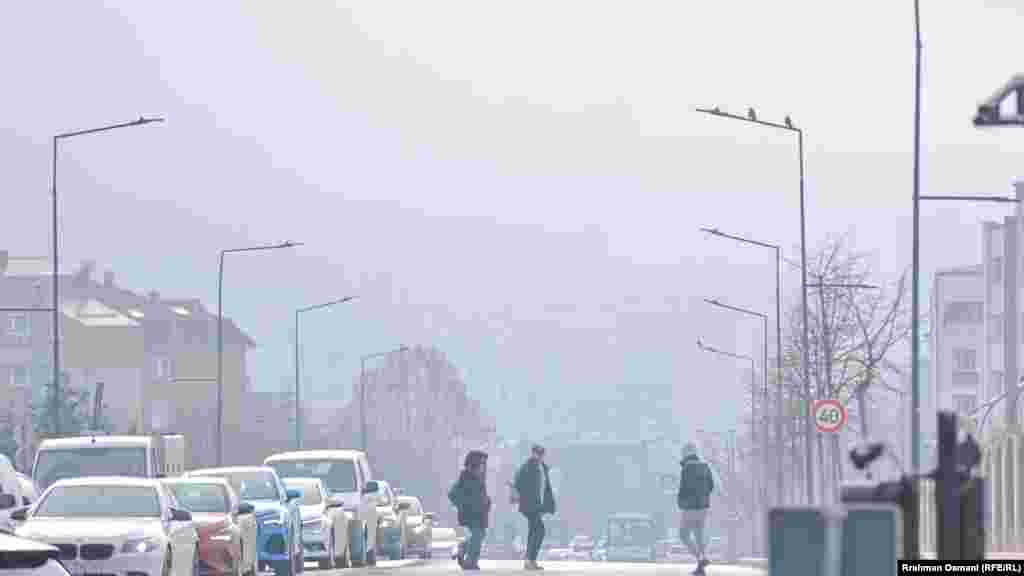 Disa qytetarë duke kaluar nëpër një rrugë të Prishtinës. Sipas Organizatës Botërore të Shëndetësisë, ndotja e ajrit është ndër kërcënimet kryesore për shëndetin e njeriut. 