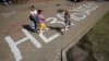 People walk along the inscription "We will not forget!" painted on the sidewalk near the place where Alyaksandr Taraykouski died amid the clashes during protests against the election results in Minsk in August 2020.